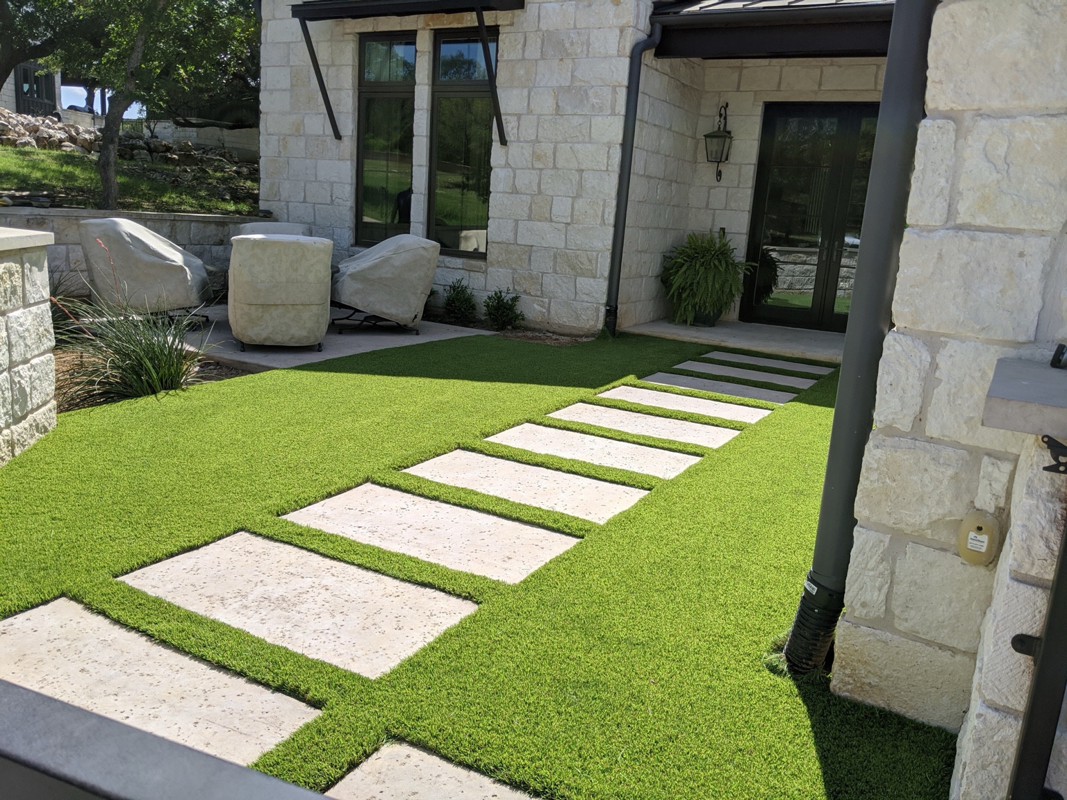 Rectangular stepping stones through turf beside a stone house