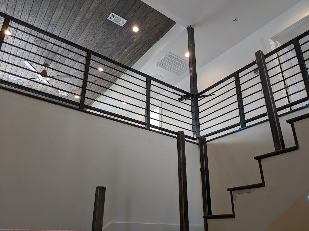 Black horizontal-bar landing and stair railings during interior installation